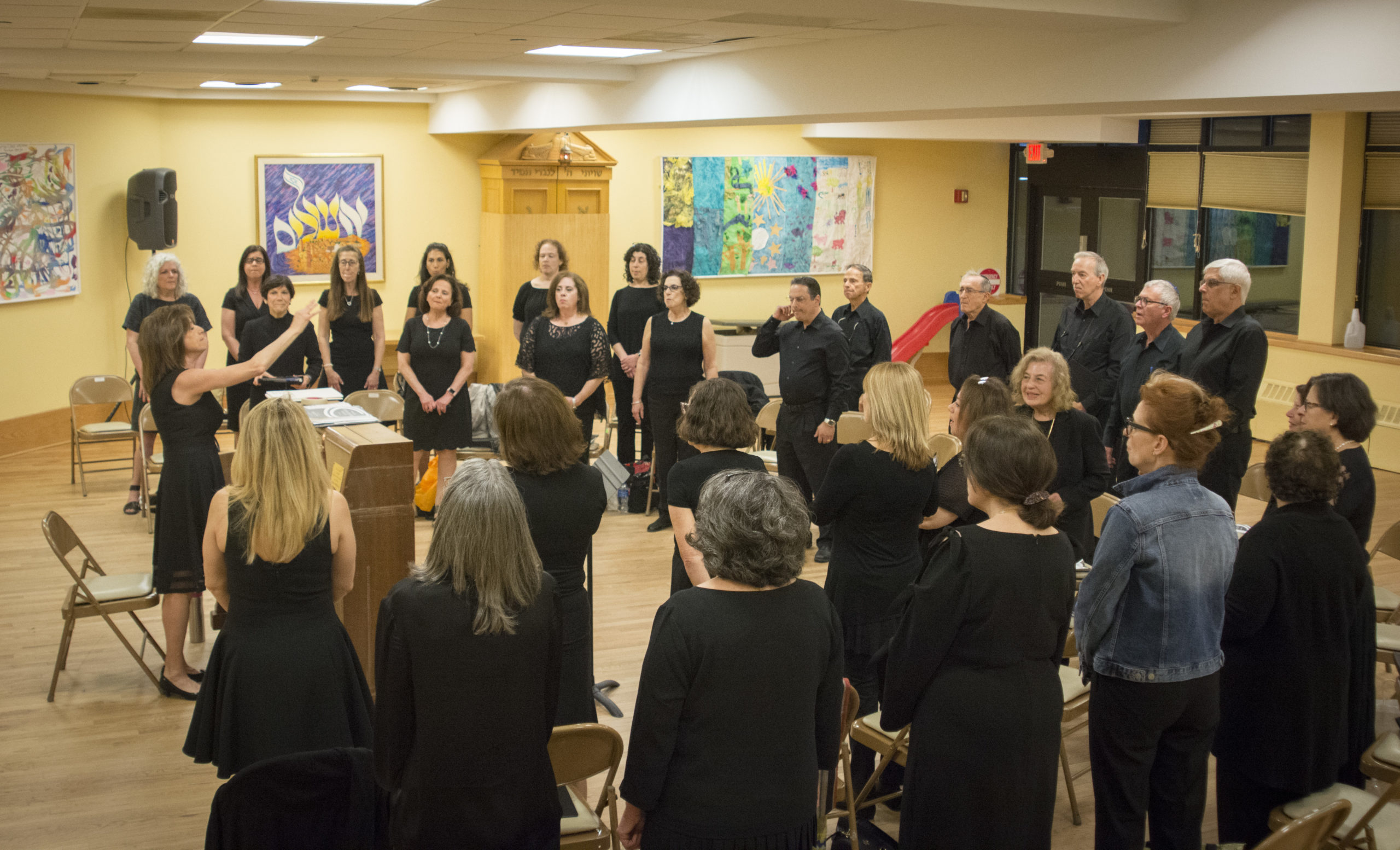 Deborah Tartell, who previously worked as a choral teacher for more than three decades, leads dozens of people through rehearsal. (Photo by Janelle Clausen)