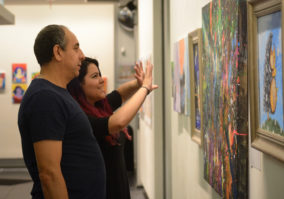 Dani Garofalo, a 17-year-old teaching assistant at the arts center, discusses some of the artwork with a patron. She said she taken great satisfaction watching some of her students grow over the years. (Photo by Janelle Clausen)