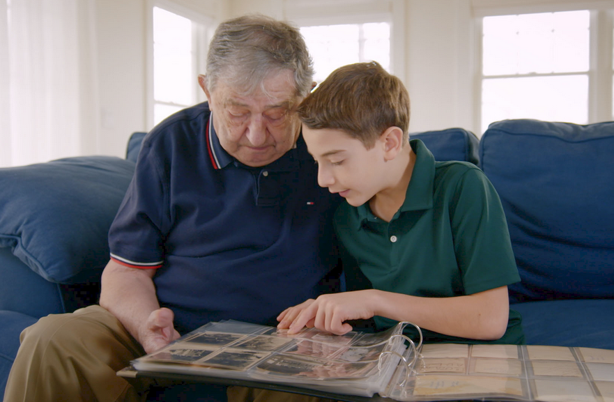 Elliot and Jack, a Holocaust survivor, sit together on the couch while going through an old photo album in "The Number on Great-Grandpa's Arm." The film will be shown on April 22. (Photo courtesy of HBO documentary films)