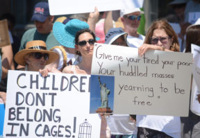 Women hold up signs calling for children to not be detained and for the nation to be more welcoming to immigrants. (Photo by Janelle Clausen)