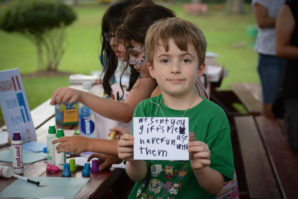 Sam Bernstein, 7, holds up a message he hopes to send to children who need help. (Photo by Janelle Clausen)