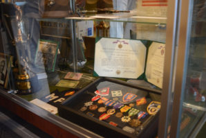 A series a medals, a trophy, photo of an army band and the uniform of a World War II sailor are among the various items on display at the Manhasset Public Library. (Photo by Janelle Clausen)
