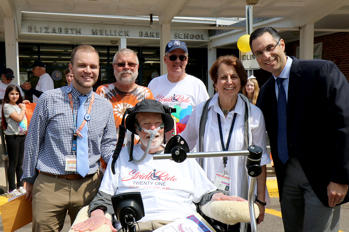 Ride for Life honoree Christopher Lynch (left) is photographed with Ride for Life founder Christopher Pendergast (center), Ride participants Paul Weisman and Nelson Colon, retired Baker Principal Sharon Fougner, and current Baker Principal Dr. Michael Grimaldi during the Ride for Life visit to E.M. Baker School in May 2018. (Photo courtesy of Great Neck Public Schools)