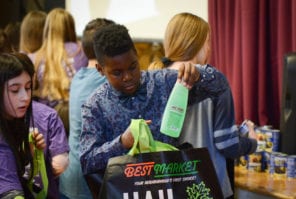 A student places a bottle inside a bag to be filled with toiletries and food to help families in need. (Photo by Janelle Clausen) 